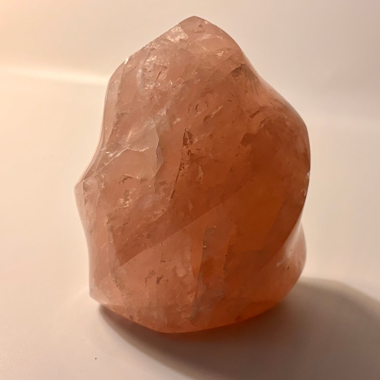 a rose quartz flame carving on a beige background
