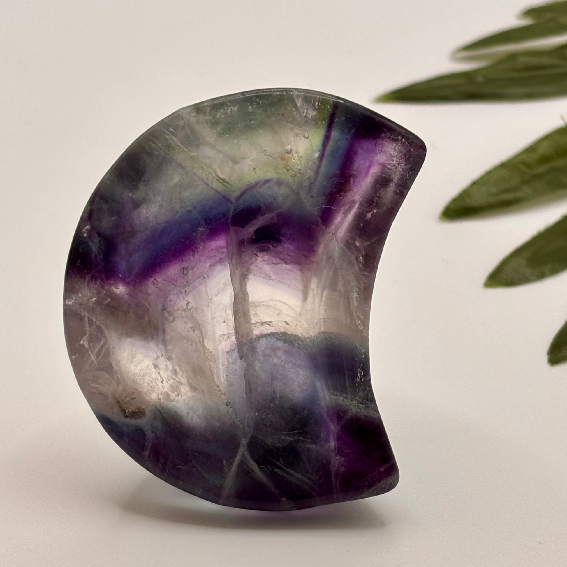 Polished purple and gray stone on a light background in purple and green on the shape of a moon