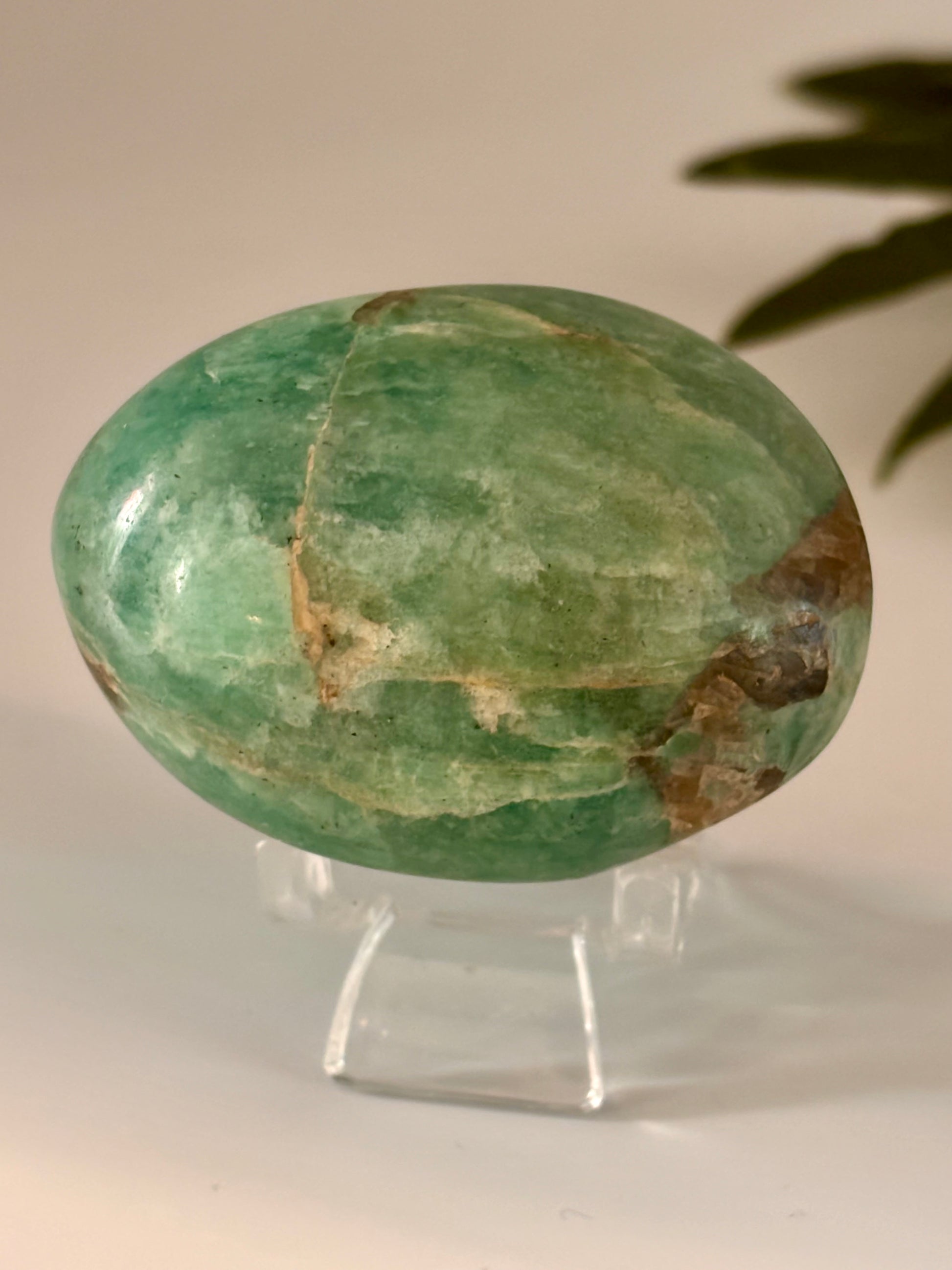 Green amazonite palm stone on a stand with a neutral background