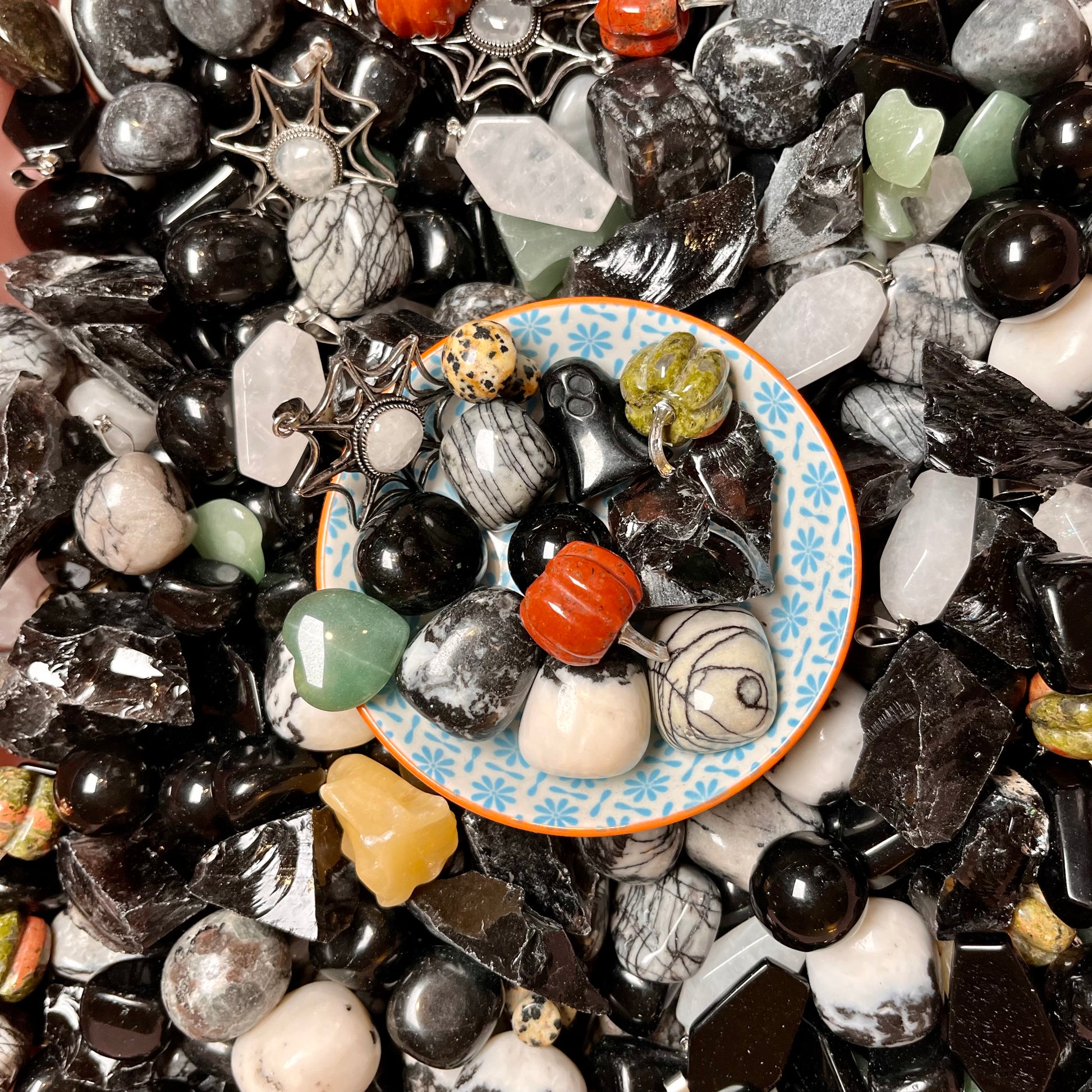 A scoop of deluxe Halloween crystal confetti containing various coloured gemstones and stones on a  plate.