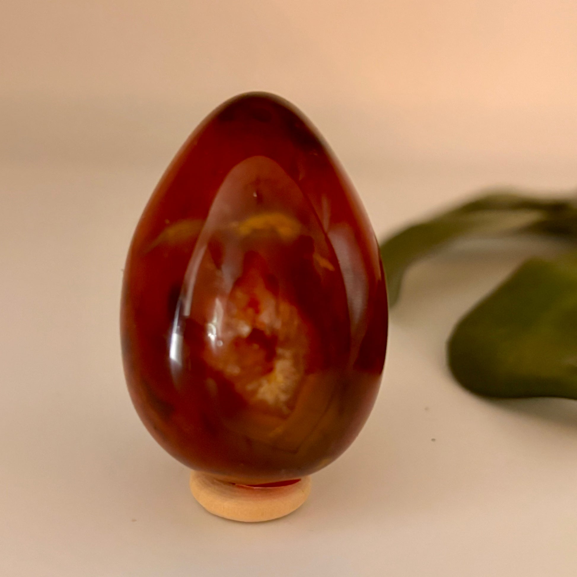 orange marbled egg-shaped object on a beige surface with a green leaf in the background