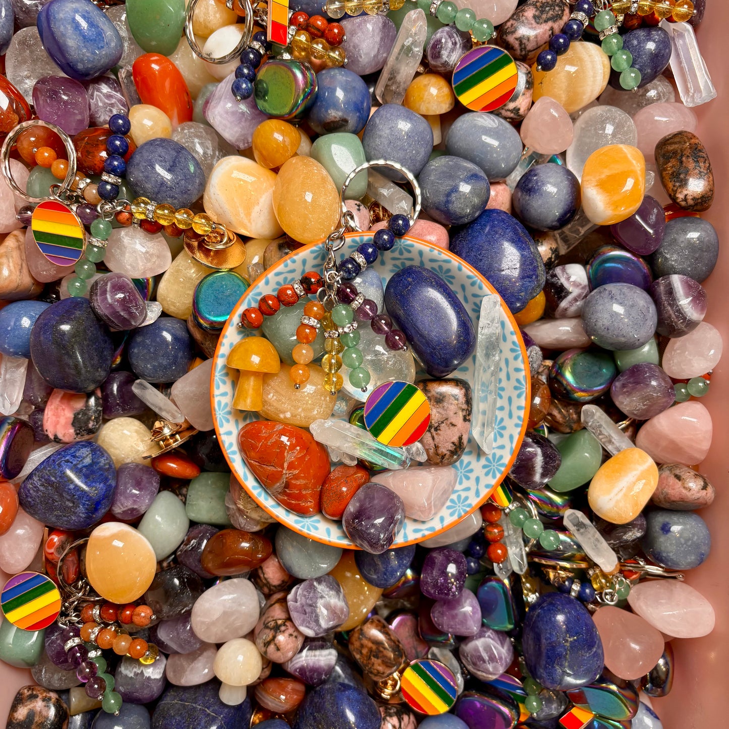 a collection of rainbow coloured crystal stones with badges to represent pride