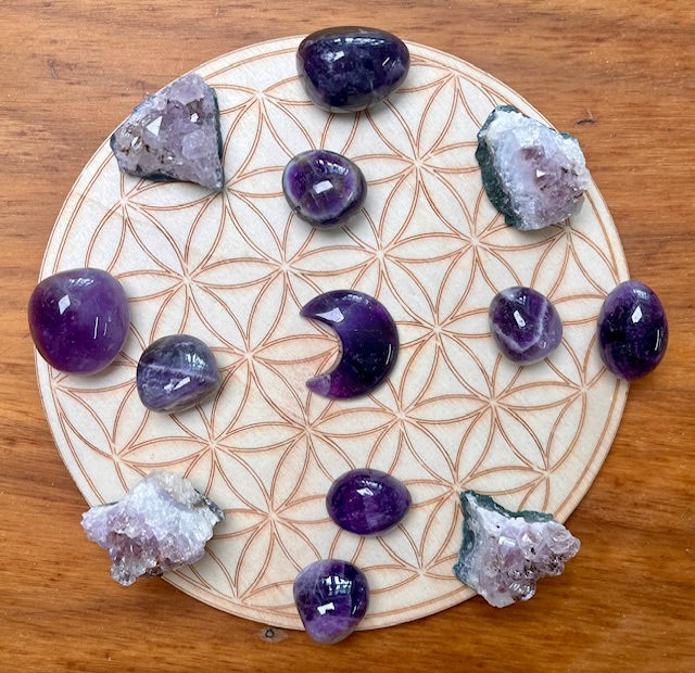 amethyst crystal grid with a moon in the centre and raw pieces and large tumbles around the edge