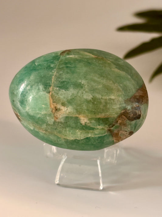 Green amazonite palm stone on a stand with a neutral background