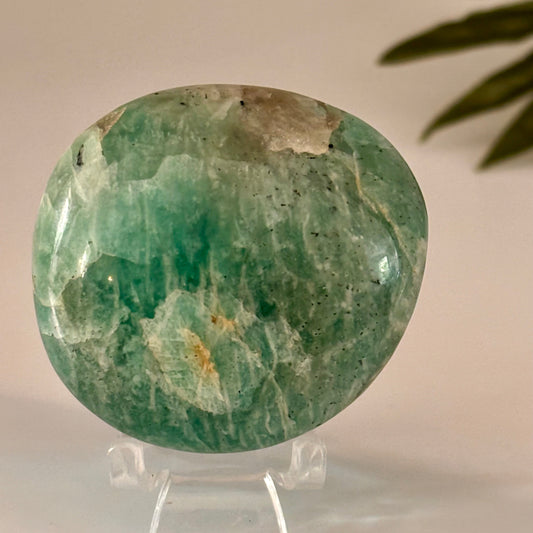 Green amazonite palm stone on a stand with a neutral background