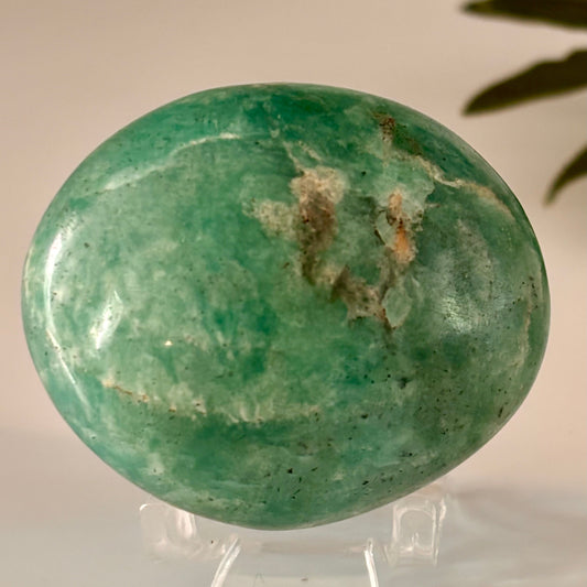Green amazonite palm stone on a stand with a neutral background