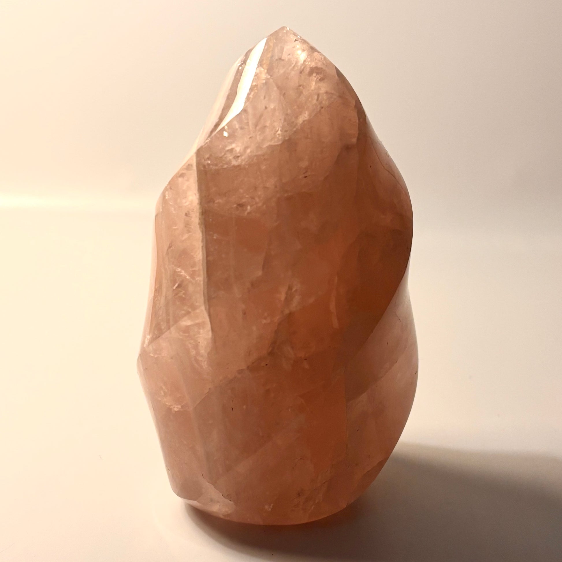 a rose quartz flame carving on a beige background