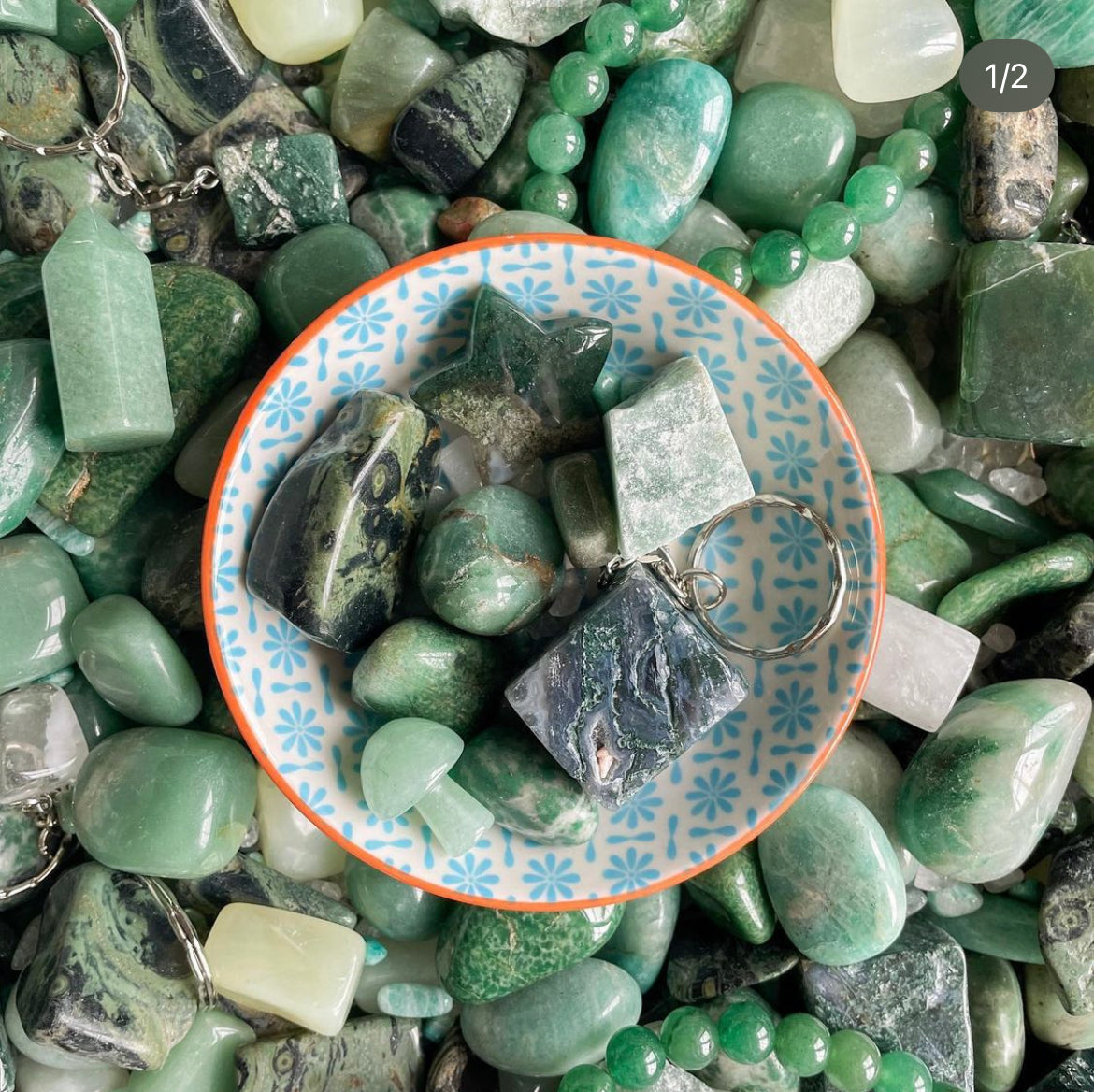 a collection of green crystals in a bowl including moss gate, green aventurine, amazonite and kambaba jasper