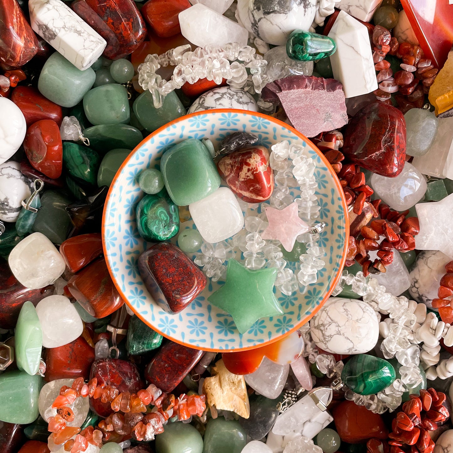 a collection of christmas colours of crystals including red jasper, rose quartz, green aventurine and malachite in  acute bowl